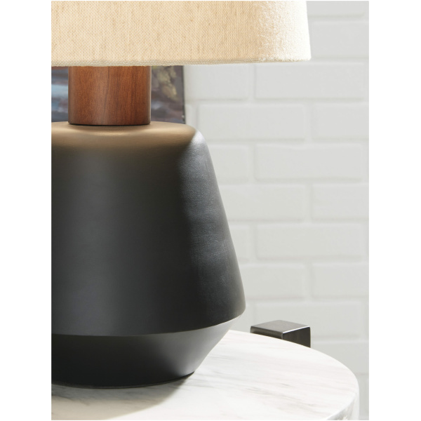 Επιτραπέζιο φωτιστικό Ancel, της Ashley, με μαύρο φινιρισμένο μέταλλο και καφέ ξύλο. Διαθέτει κυλινδρικό του καπέλο, σε απαλή μπεζ απόχρωση.