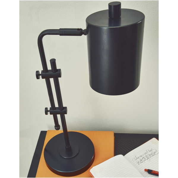 Μεταλλικό επιτραπέζιο φωτιστικό Baronvale, της Ashley. Διαθέτει βιομηχανικό design, μαύρο χρώμα και ρυθμιζόμενο λαιμό και καπέλο.