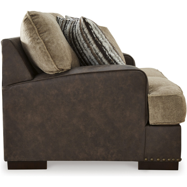 Διθέσιος καναπές Ashley Enderlin, με δύο χρωματικούς τόνους. Έχει τρία διακοσμητικά μαξιλάρια, διακοσμητικούς καμπαράδες και εμφανή ορθογώνια πόδια.